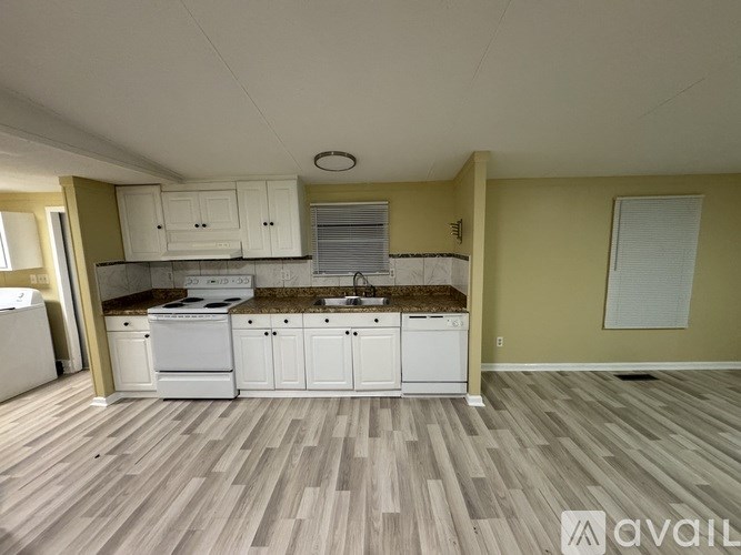 A kitchen with white appliances and cabinets is available for rent.