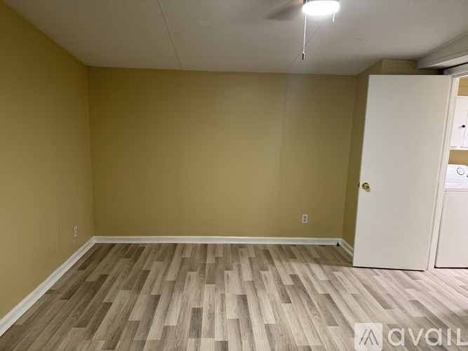 A room with wooden flooring and a white door.
