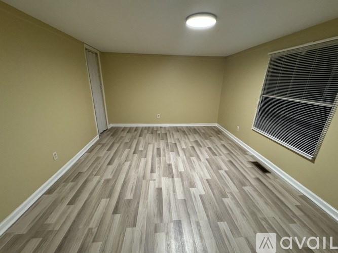 A room with wooden flooring and a window with blinds.