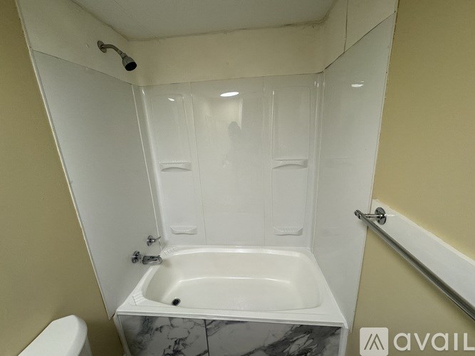 A white bathroom with a tub, toilet, and shower.