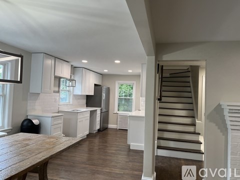 A modern kitchen with white cabinets and a wooden table.