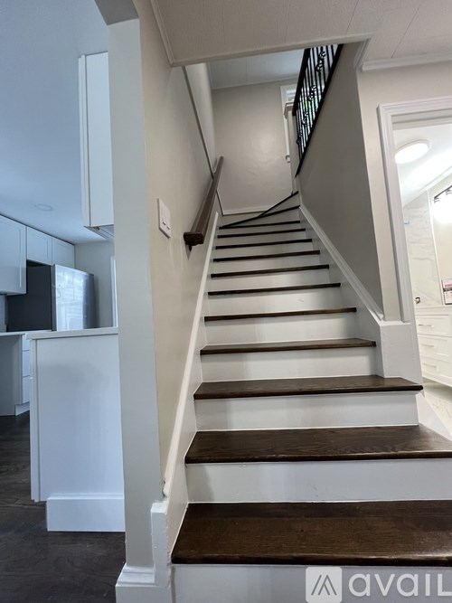 A staircase with a wooden handrail and white walls.