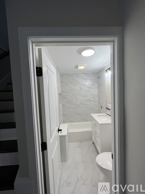 A bathroom with a toilet, sink and bathtub is visible through an open door.