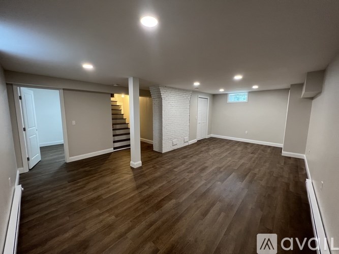 A spacious room with wooden flooring and white walls.