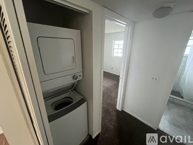 A small, white, built-in refrigerator with a freezer drawer is in a room with a carpeted floor.