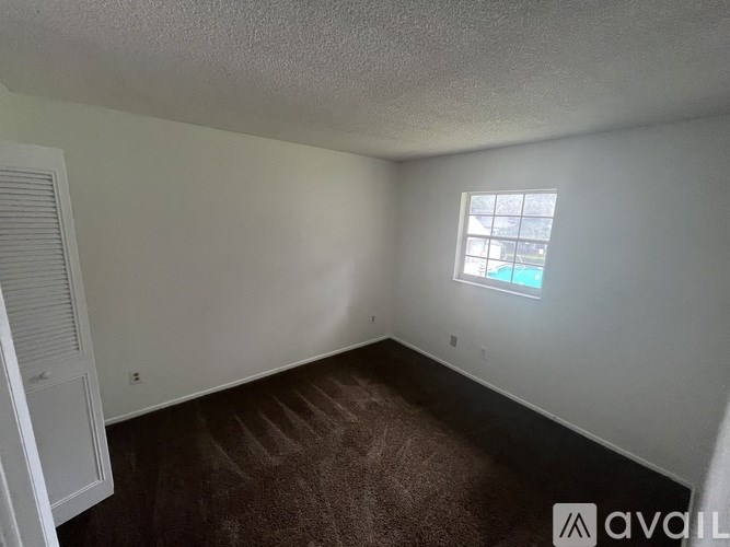 A room with a carpeted floor and a window letting in light.