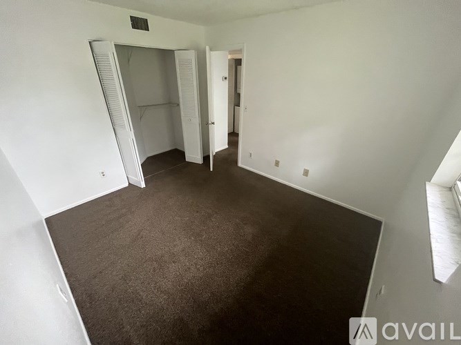 A room with a carpeted floor and a white wall with a doorway leading to another room.