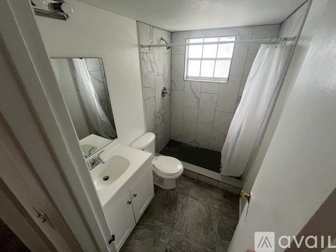 A bathroom with a toilet, sink, and shower.