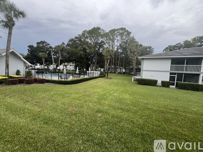A grassy area with a house and trees in the background.