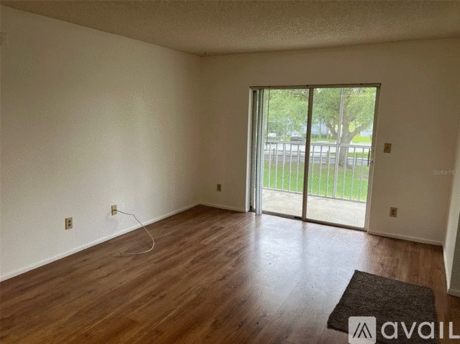 Empty room with wooden floor and sliding glass door.