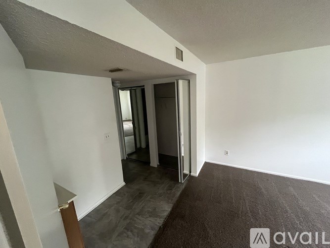 A room with a carpeted floor and a white wall with a doorway leading to another room.