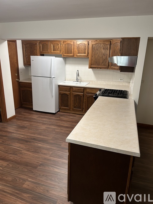 A kitchen with a white fridge and wooden cabinets.