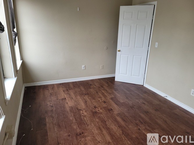 A room with a white door and wooden flooring.