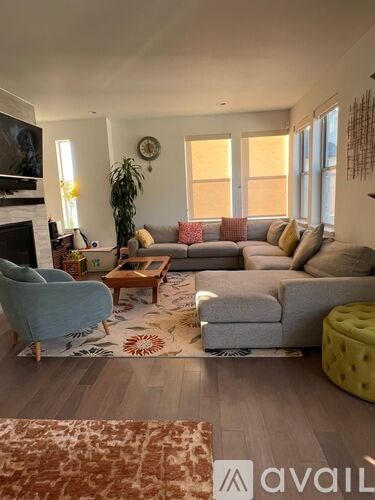 A living room with a grey couch, a blue armchair, a wooden coffee table, and a rug with a pattern.