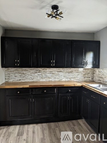 A kitchen with black cabinets and a wooden countertop.