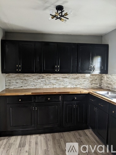 A kitchen with black cabinets and a wooden countertop.