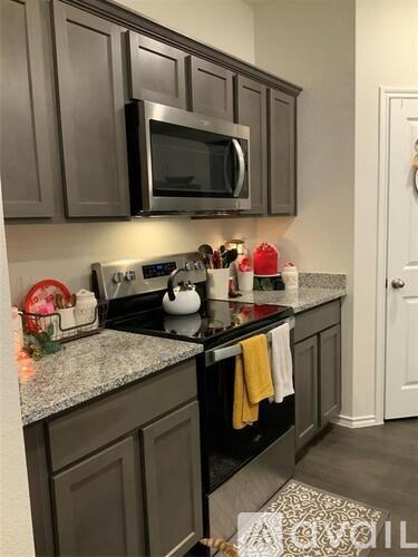A kitchen with dark brown cabinets and a granite countertop.