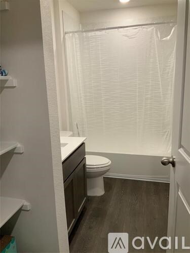 A white toilet sits in a small bathroom with a walk-in shower.