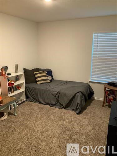 A bedroom with a bed, a nightstand, and a window with blinds.