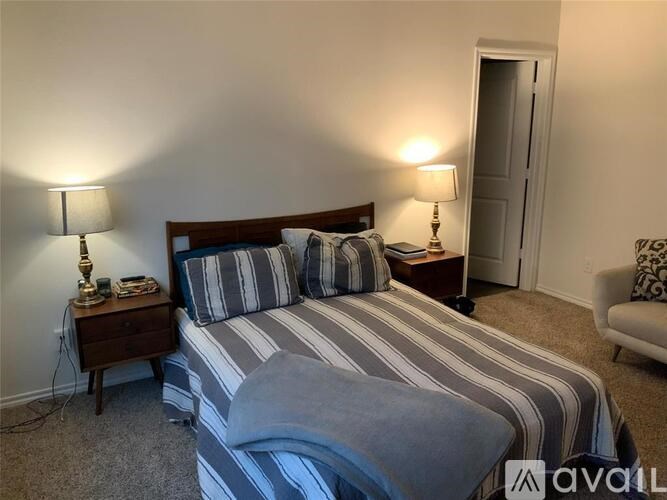 A bedroom with a bed, nightstand, and lamp.