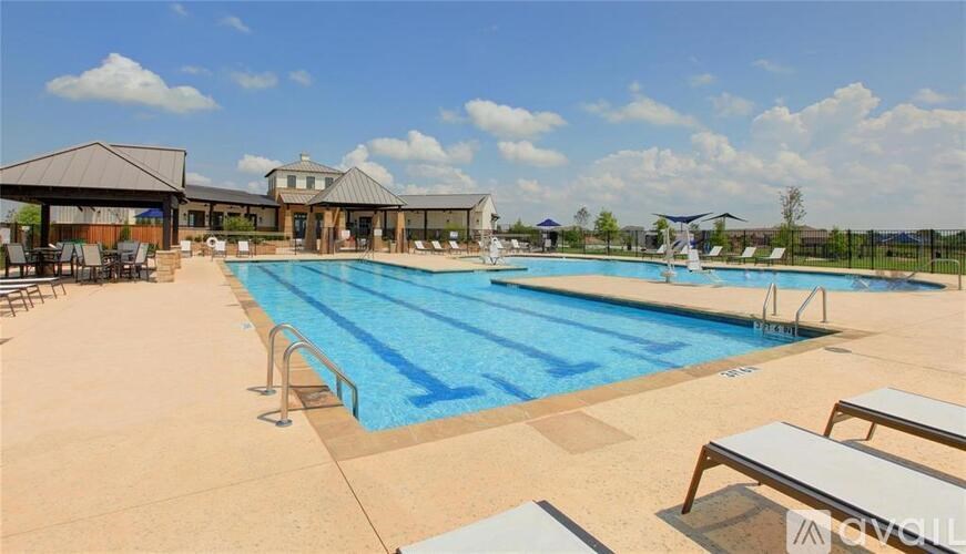 A large outdoor swimming pool with sun loungers and a building in the background.