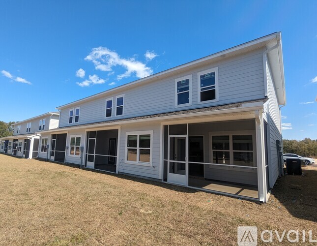 A white mobile home with a porch and multiple windows.