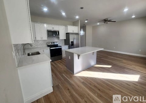 A kitchen with white cabinets and a wooden floor.