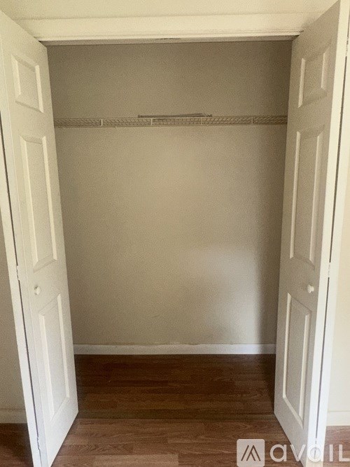 A white door is open to a room with a wooden floor and a white wall.