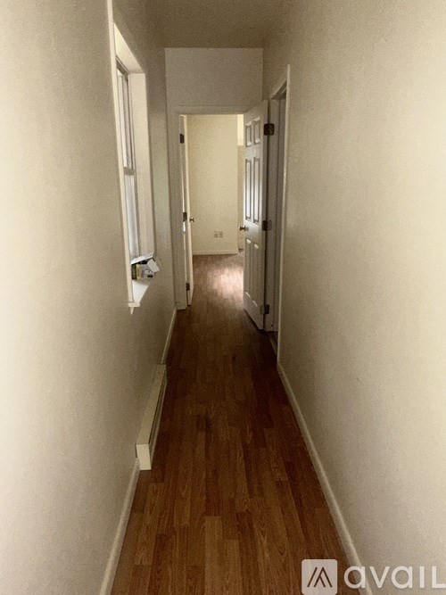 A long hallway with wood floors and white walls.