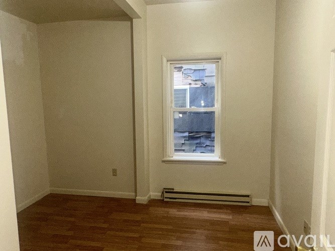 A room with a window and a radiator on the floor.