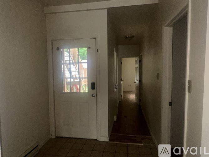 A hallway with a white door and tiled floor.