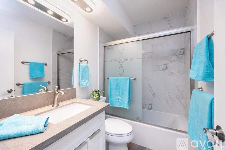 A bathroom with a white toilet, a sink with a mirror above it, and a glass shower door.