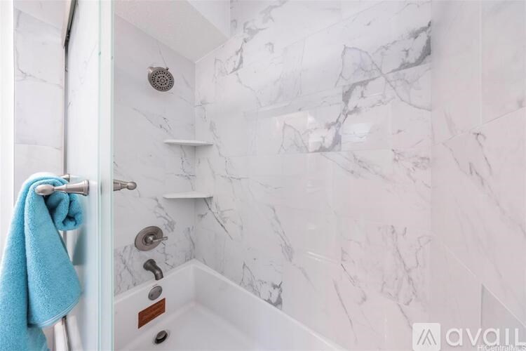 A white marble bathroom with a blue towel hanging on the door.