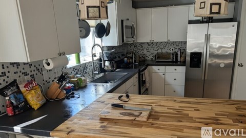 A kitchen with a wooden counter top and white cabinets.
