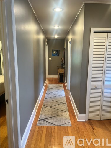 A hallway with a rug on the floor and a door on the right.
