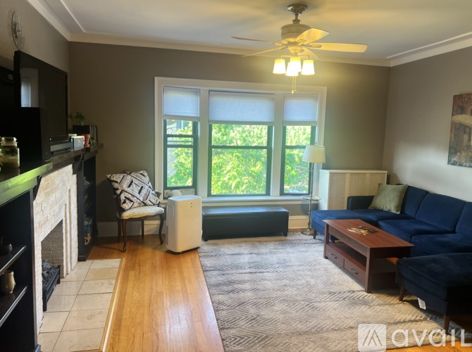 A living room with a fireplace, a blue couch, and a ceiling fan.
