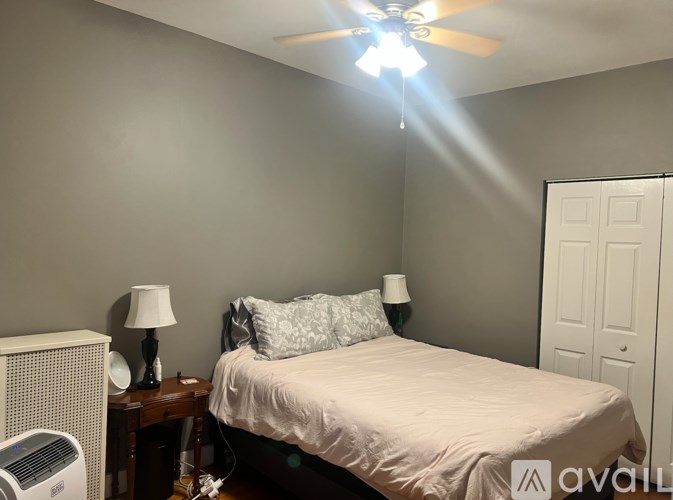 A bedroom with a bed, nightstand, and a ceiling fan.