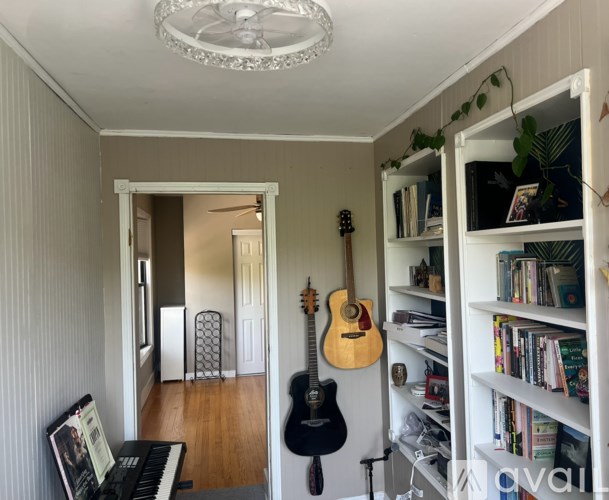 A room with a guitar hanging on the wall and a bookshelf filled with books.
