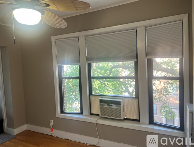 A room with a window, a fan, and a wall-mounted air conditioner unit.