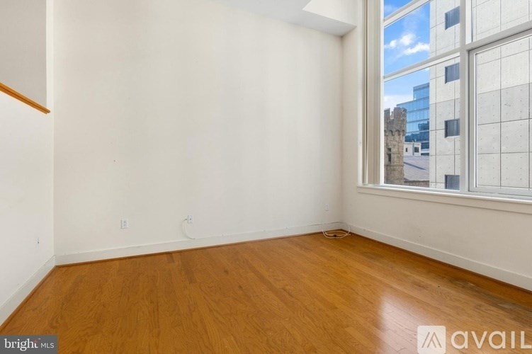 A room with wooden flooring and a window overlooking a cityscape.