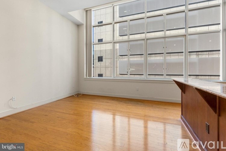 A room with wooden floors and a large window with a view of a building outside.