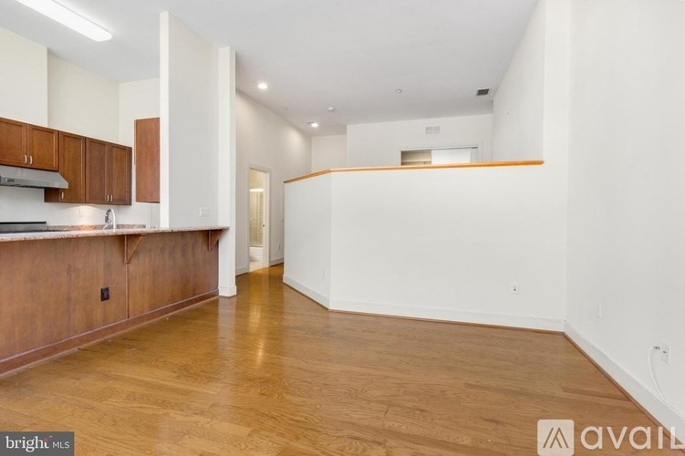 A spacious kitchen with wooden floors and white walls.