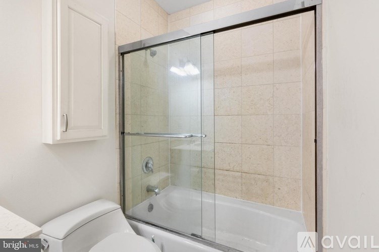 A bathroom with a toilet, a glass shower door, and a tiled wall.