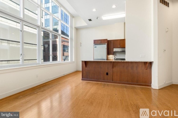 A spacious room with wooden floors and a kitchenette area.