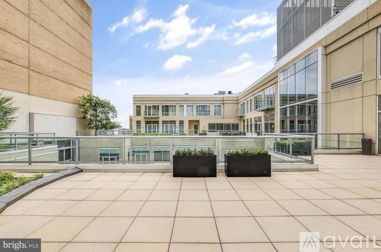 A modern building with a glass facade and a courtyard with planters.