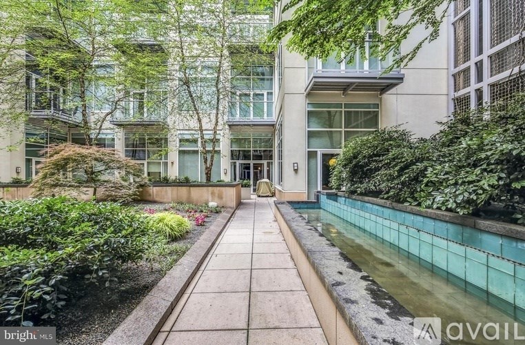 A modern building with a glass facade and a walkway leading to the entrance.