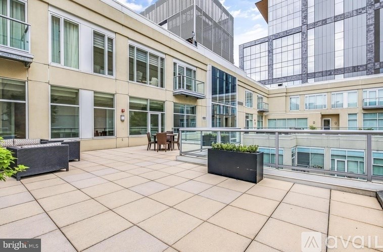 A balcony with a table and chairs overlooks a cityscape.