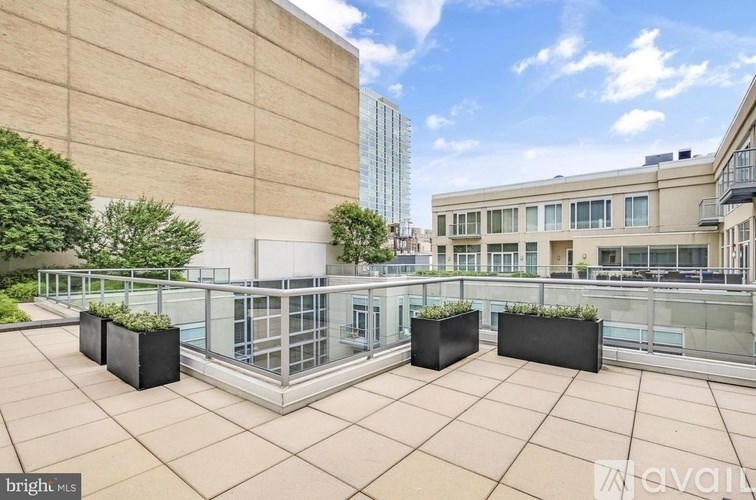 A rooftop patio with a glass railing and planters.