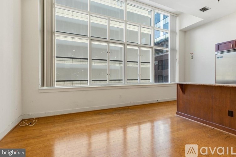 A room with a large window and wooden flooring is available for rent.