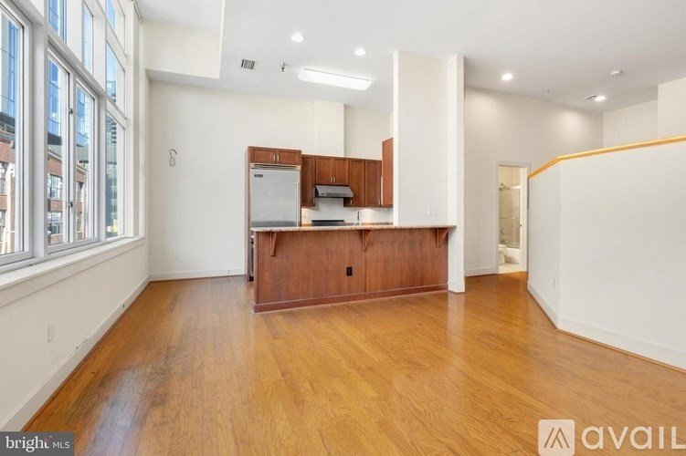 A spacious kitchen with wooden floors and white walls.
